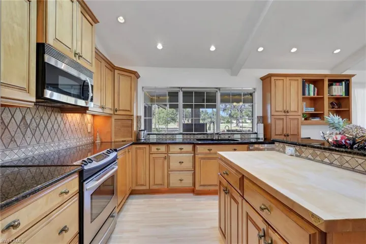 Kitchen featuring tasteful backsplash, appliances with stainless steel finishes, beam ceiling, open shelves, and light wood-style floors