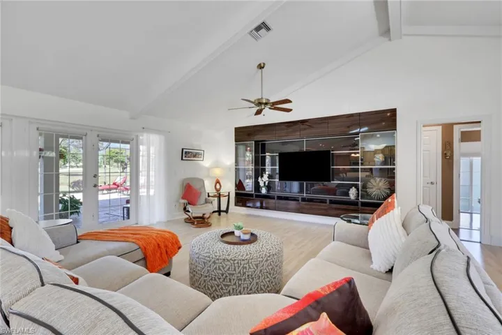 Living room featuring beam ceiling, french doors, high vaulted ceiling, and wood finished floors