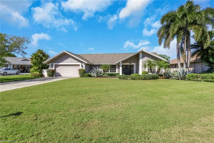 Ranch-style home featuring stucco siding, driveway, a front yard, and an attached garage