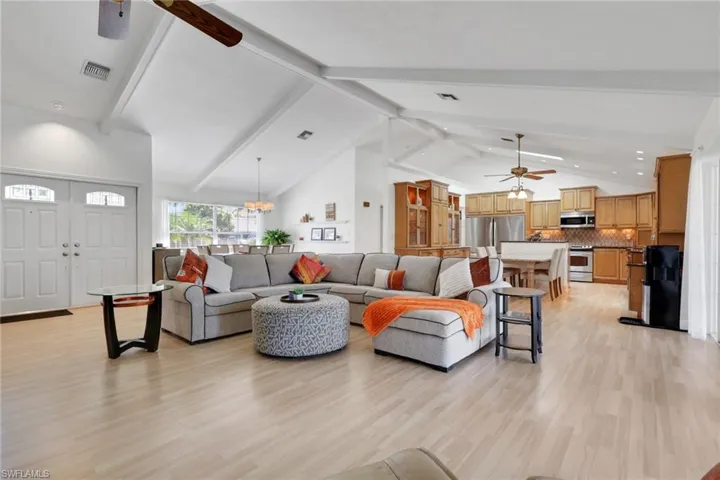 Living area featuring ceiling fan, beam ceiling, high vaulted ceiling, and light wood-style floors