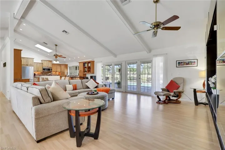 Living area with ceiling fan, french doors, beam ceiling, light wood finished floors, and high vaulted ceiling