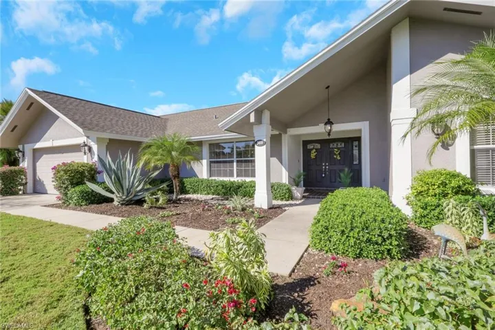 Doorway to property with stucco siding, a garage, and roof with shingles