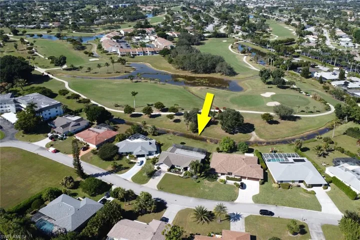 Aerial overview of property's location featuring nearby suburban area, a large body of water, and a local golf course