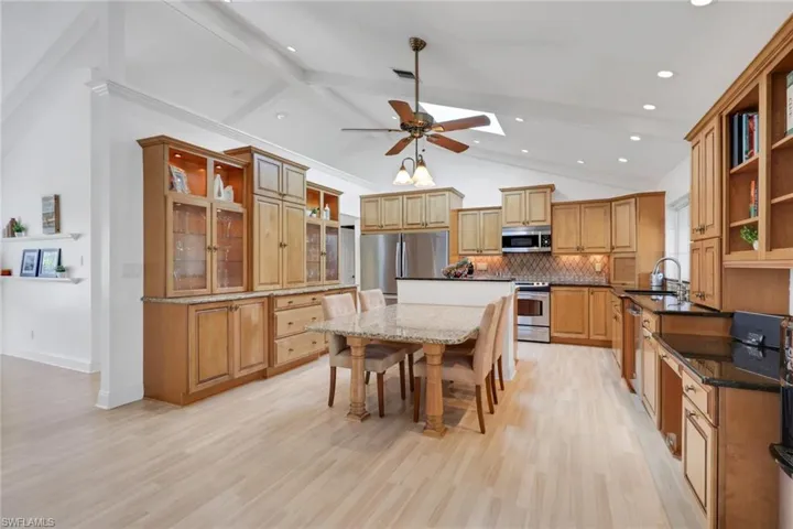 Kitchen with open shelves, a breakfast bar area, a kitchen island, light wood-type flooring, and tasteful backsplash