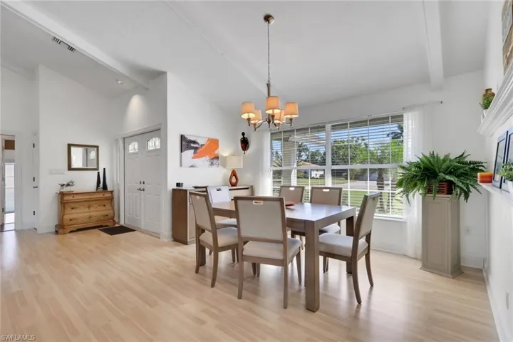 Dining space with light wood-style floors, high vaulted ceiling, and a chandelier