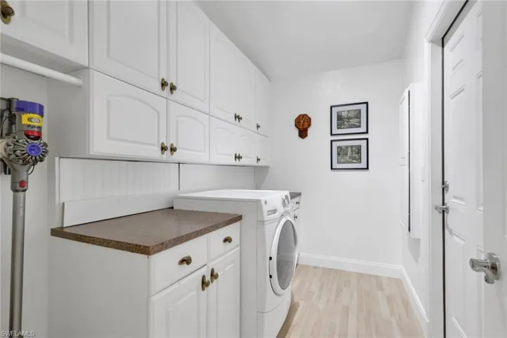 Laundry area with cabinet space, light wood finished floors, and washer and clothes dryer