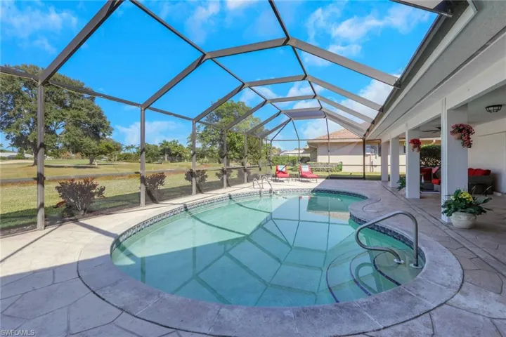 Outdoor pool with a patio, glass enclosure, a sunroom, and a lawn