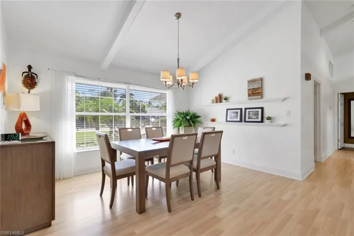 Dining space featuring beam ceiling, light wood-style floors, a chandelier, and high vaulted ceiling