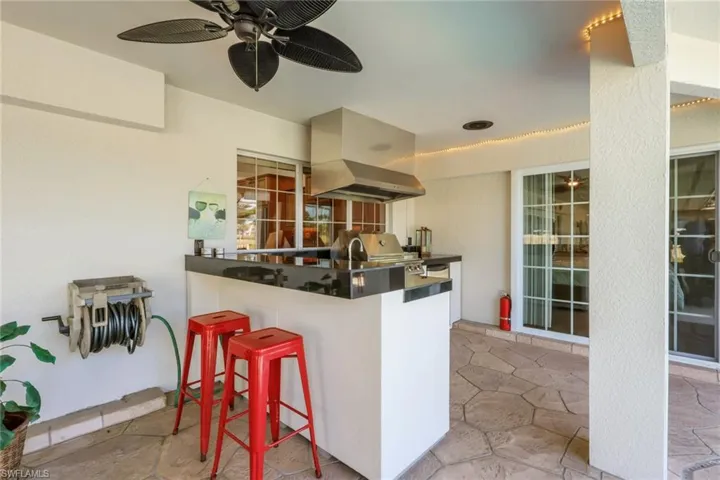 Kitchen featuring dark countertops, stone tile floors, ceiling fan, a kitchen breakfast bar, and extractor fan