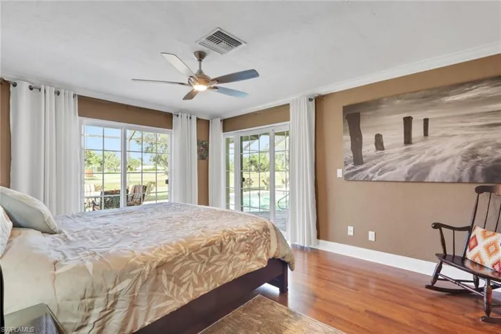 Bedroom with access to exterior, wood finished floors, ceiling fan, and ornamental molding