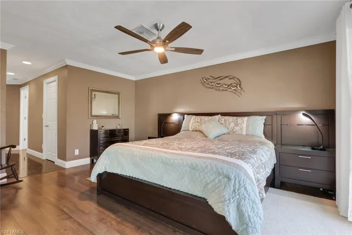 Bedroom with crown molding, wood finished floors, and a ceiling fan
