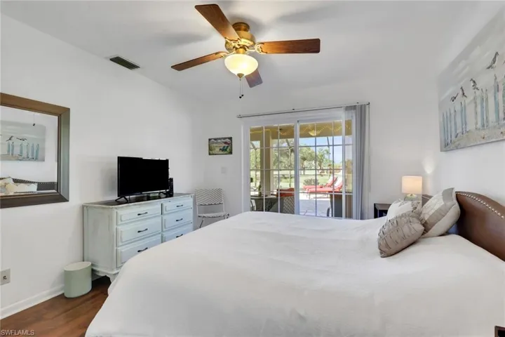 Bedroom with dark wood-style floors, ceiling fan, and access to outside
