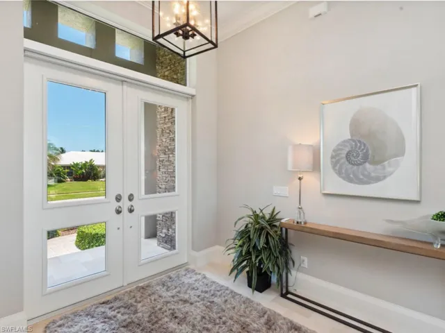 Foyer entrance featuring an inviting chandelier, french doors, and ornamental molding