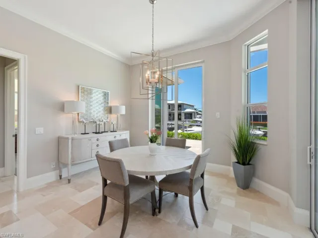 Dining space with a notable chandelier, light tile patterned flooring, and ornamental molding