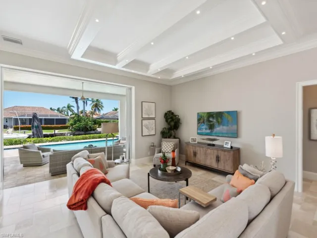 Living room with crown molding, beam ceiling, and light tile patterned floors