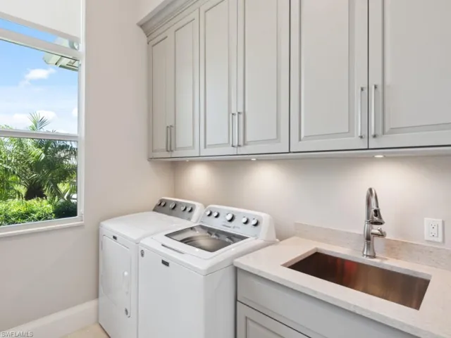 Laundry room with washing machine and dryer, sink, and cabinets