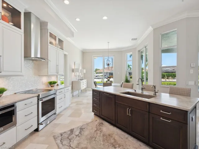 Kitchen featuring stainless steel electric range, wall chimney range hood, decorative backsplash, sink, and light tile patterned floors