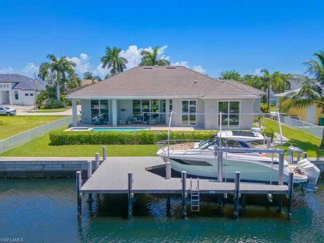 Back of property with a patio area, a water view, and a lawn