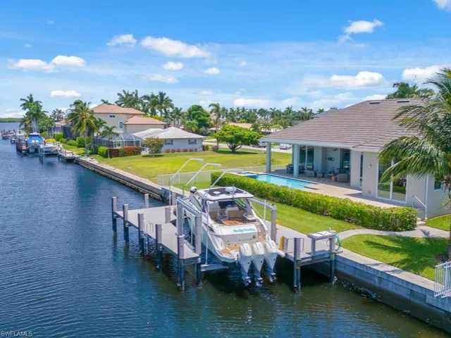 Dock area with a patio, a water view, and a yard