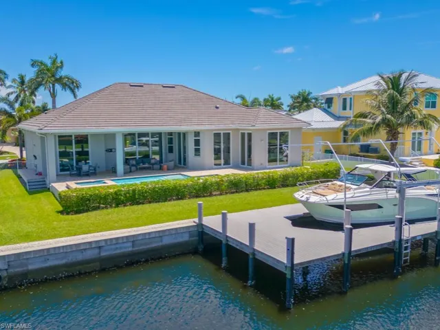 Rear view of property with a water view, a patio area, and a yard