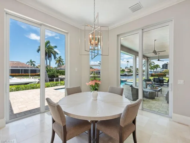 Dining area with light tile patterned flooring, crown molding, and ceiling fan with notable chandelier