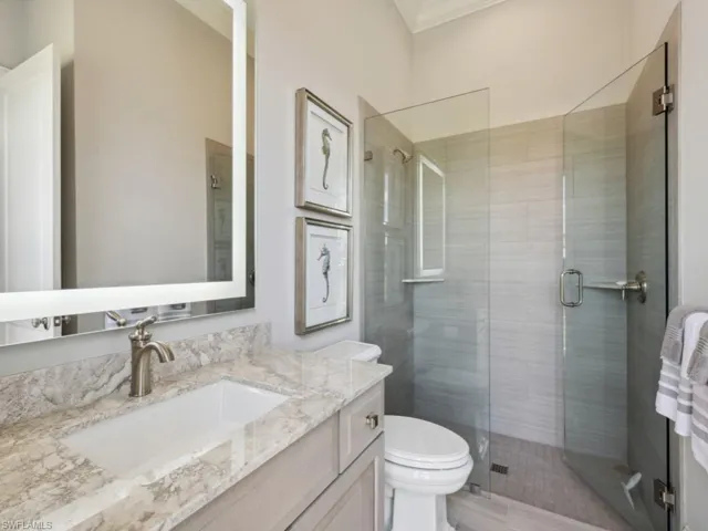 Bathroom with vanity, a shower with shower door, toilet, and crown molding