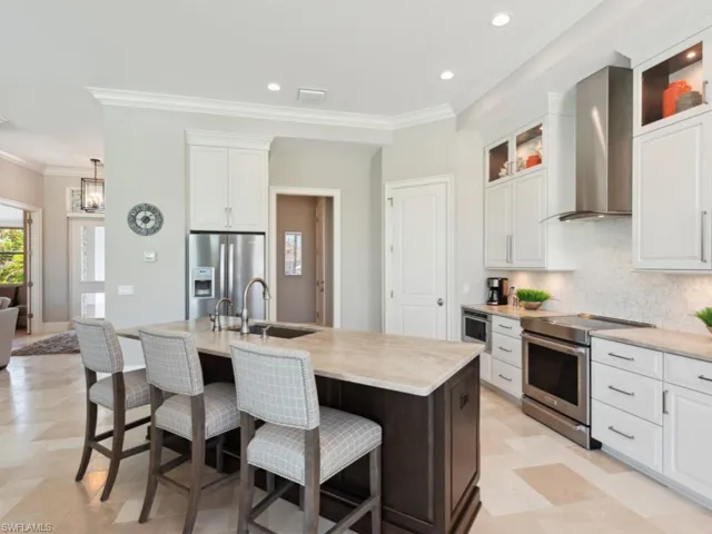 Kitchen with an island with sink, range with electric stovetop, wall chimney range hood, stainless steel fridge with ice dispenser, and white cabinetry