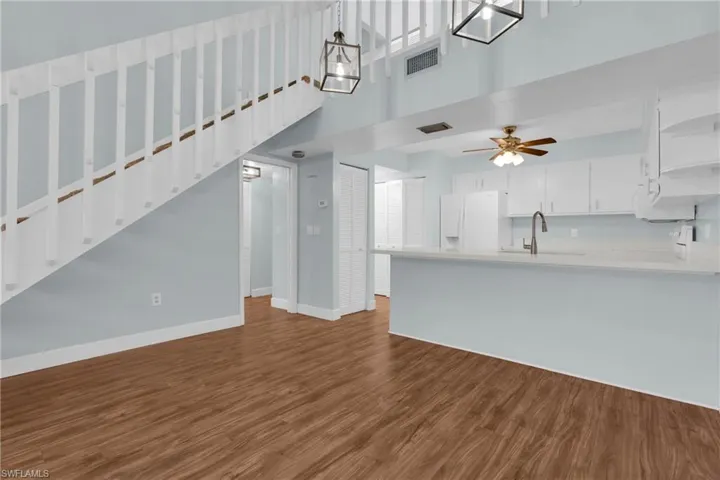 Kitchen with white cabinetry, a high ceiling, white refrigerator with ice dispenser, dark wood finished floors, and open floor plan