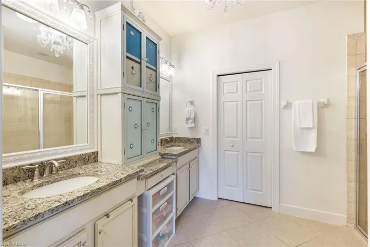 Full bathroom featuring a stall shower, a chandelier, light tile patterned floors, vanity, and a closet