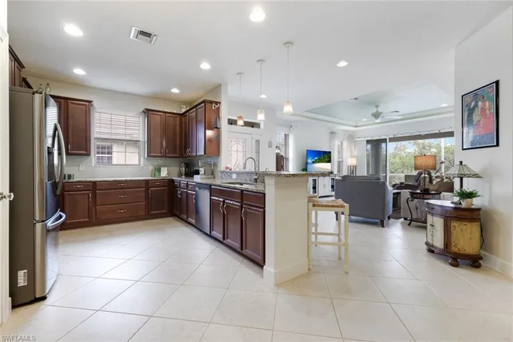 Kitchen featuring light stone counters, stainless steel appliances, a breakfast bar area, open floor plan, and pendant lighting