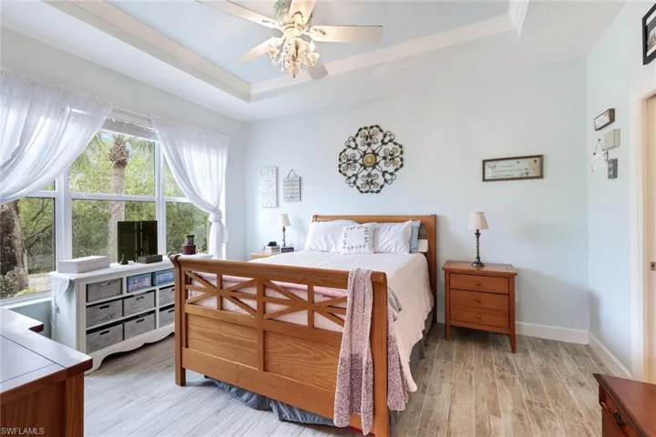 Bedroom featuring a tray ceiling, light wood finished floors, and a ceiling fan