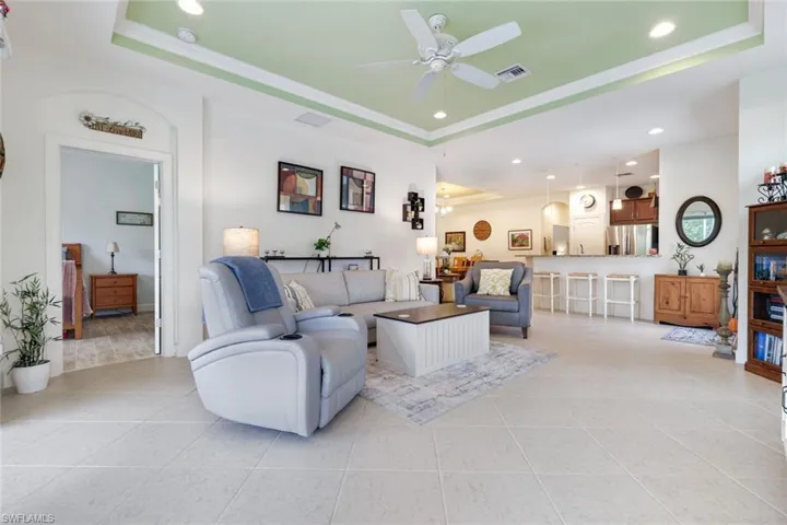 Living room featuring a tray ceiling, recessed lighting, light tile patterned floors, and ceiling fan