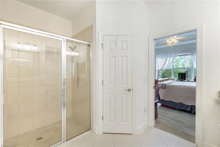 Ensuite bathroom with a stall shower, tile patterned flooring, and a chandelier