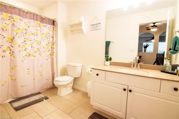 Full bath featuring a ceiling fan, toilet, vanity, tile patterned flooring, and curtained shower