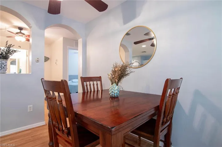 Dining area with ceiling fan, light wood-style flooring, baseboards, and arched walkways
