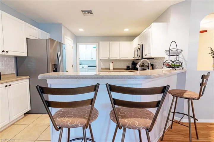 Kitchen featuring stainless steel appliances, independent washer and dryer, tasteful backsplash, white cabinets, and recessed lighting