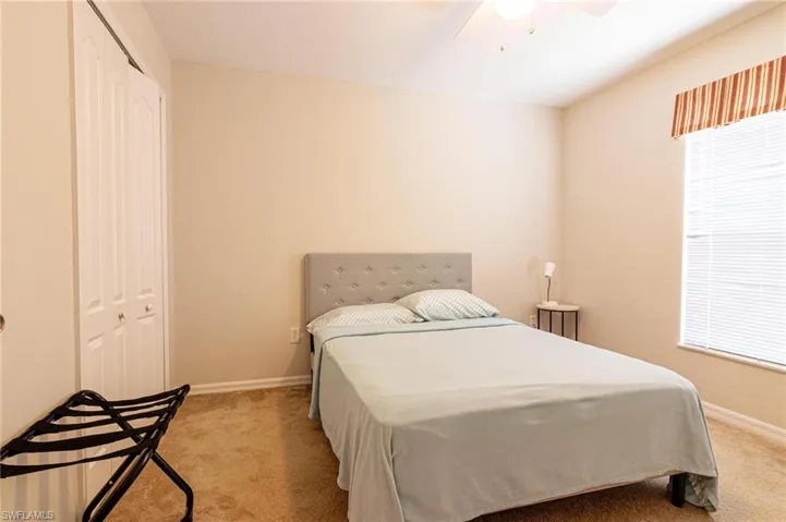 Carpeted bedroom with a closet, baseboards, multiple windows, and ceiling fan