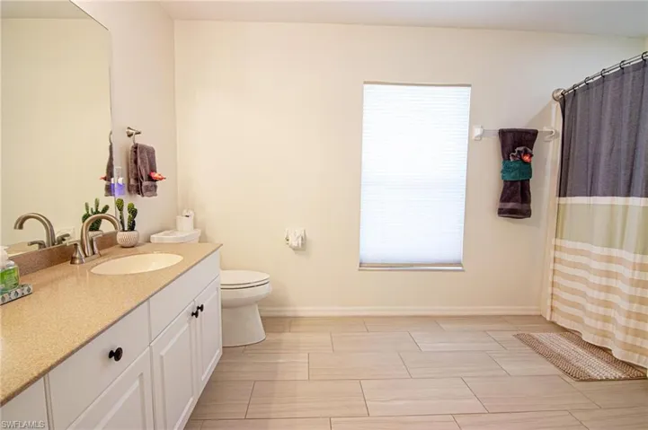 Bathroom with toilet, vanity, baseboards, and a shower with curtain