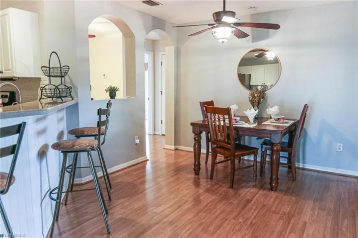 Dining space featuring arched walkways, wood finished floors, a ceiling fan, and baseboards