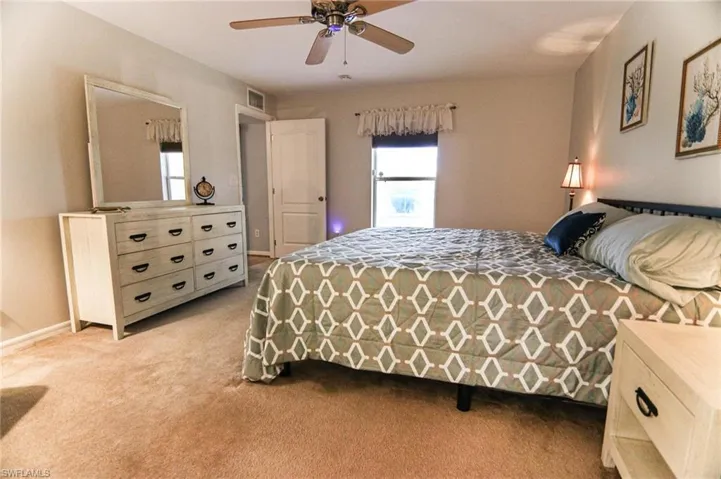 Bedroom featuring light carpet, ceiling fan, and baseboards