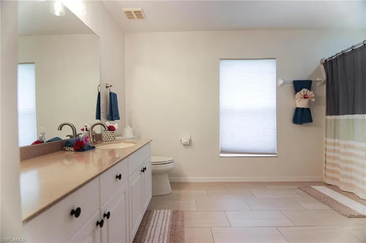 Full bath featuring vanity, toilet, and baseboards