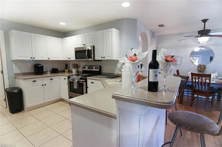 Kitchen with stainless steel appliances, a peninsula, a breakfast bar area, white cabinets, and recessed lighting