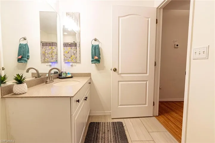 Full bathroom featuring vanity, baseboards, and wood finished floors