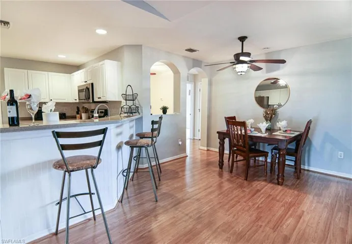 Kitchen featuring stainless steel microwave, arched walkways, a breakfast bar area, baseboards, and recessed lighting