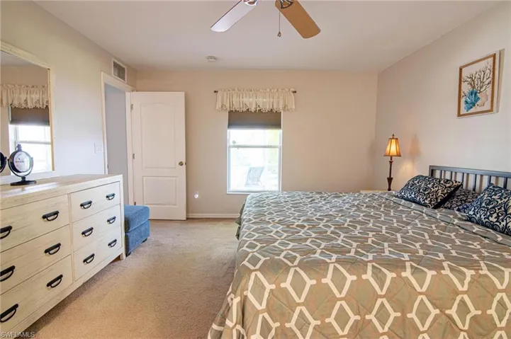 Bedroom featuring light carpet, a ceiling fan, and baseboards