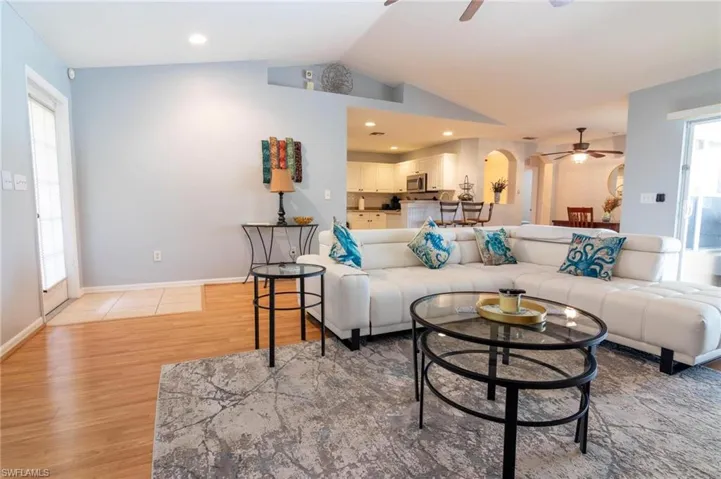 Living area featuring ceiling fan, lofted ceiling, arched walkways, light wood-type flooring, and healthy amount of natural light