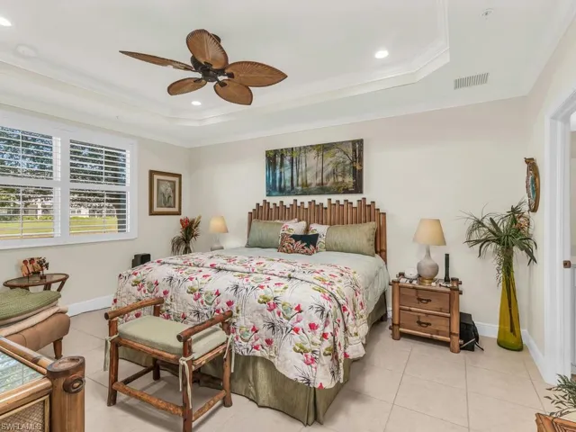 Tiled bedroom featuring a raised ceiling, ceiling fan, and crown molding