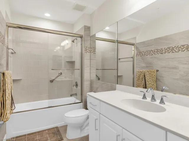 Full bathroom with combined bath / shower with glass door, vanity, toilet, and tile patterned flooring