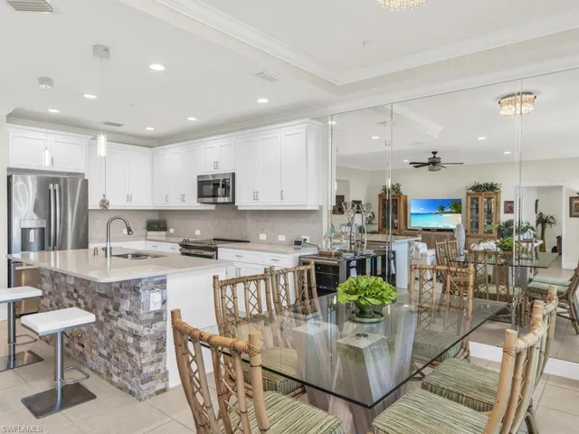 Tiled dining area with ceiling fan with notable chandelier, ornamental molding, and sink