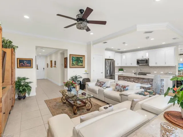Living room with light tile patterned floors, ceiling fan, and ornamental molding